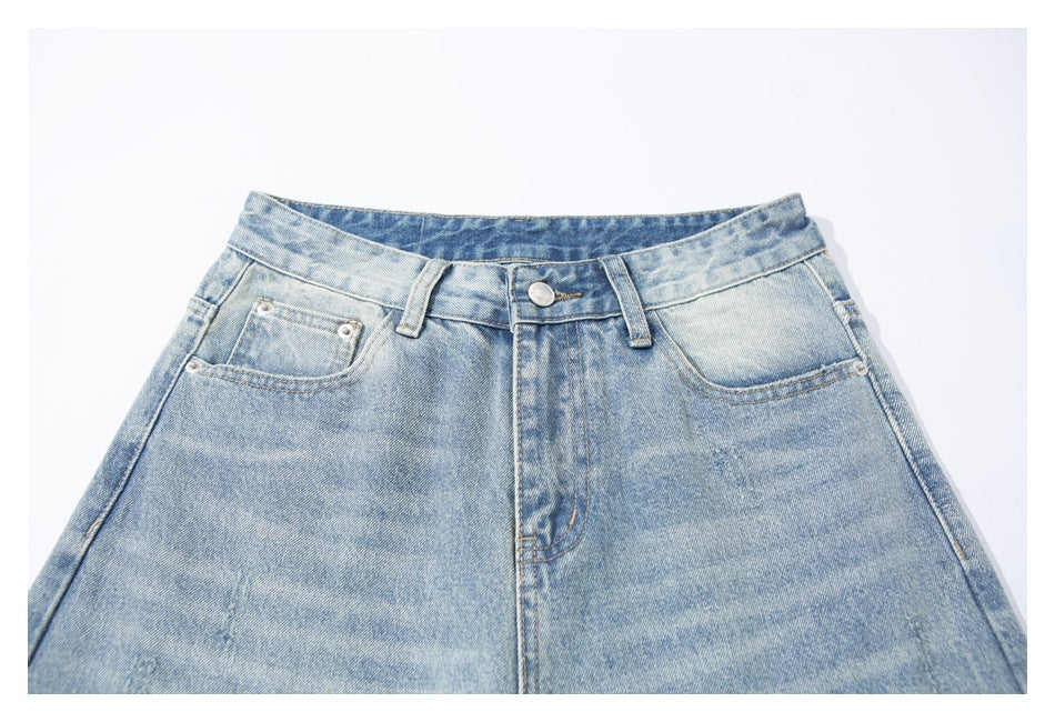Front view of light-wash jeans laid flat, focused on the waistband, button, belt loops and front pockets.