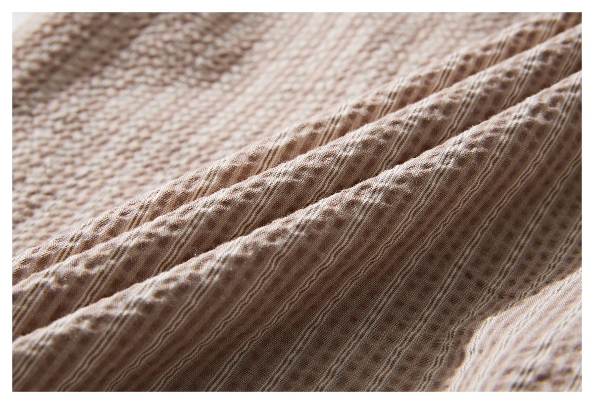 Close-up of taupe-brown fabric with fine stripes and a puckered, textured surface.