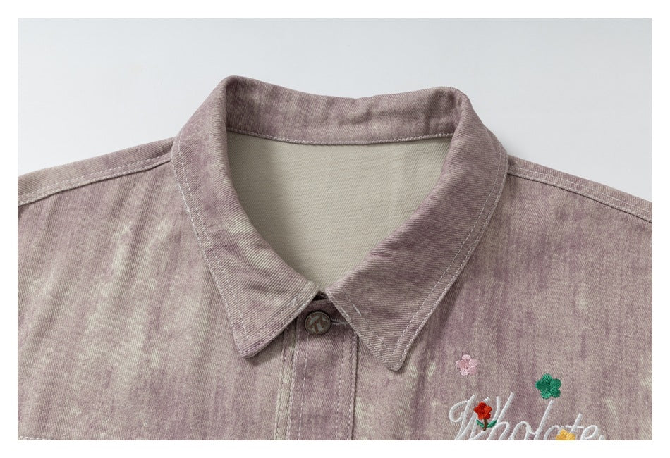 Close-up of the jacket's pointed collar, top button, mauve washed fabric, and small floral embroidery.