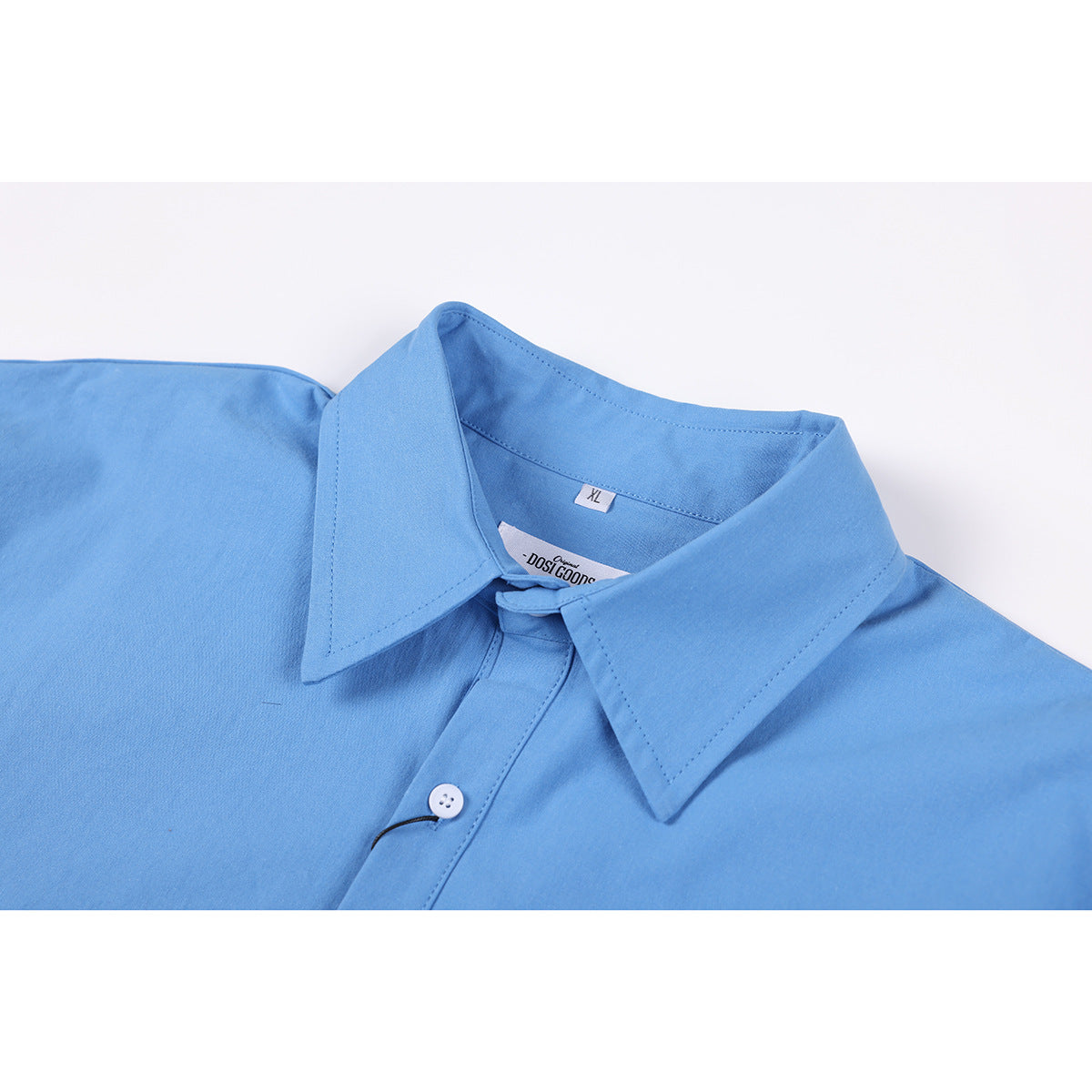 Close-up of a light blue shirt collar, white button, and inner neck labels.
