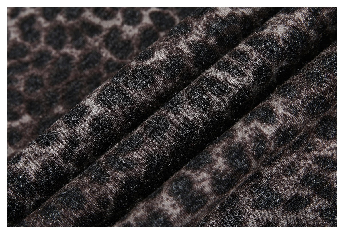 Macro view of dark leopard-print fabric gathered into folds, showing its textured surface.