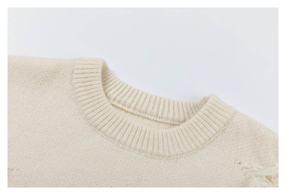 Close-up of the ribbed crew neckline and knit texture of an ivory sweater.