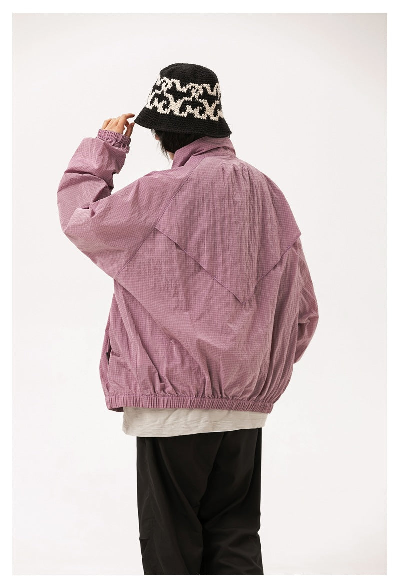 Rear view of a model wearing a loose mauve jacket with a layered back flap, elastic cuffs and hem.