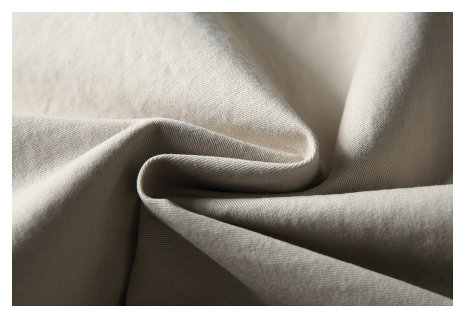 Close-up of beige fabric draped to show its fine diagonal weave and soft folds.