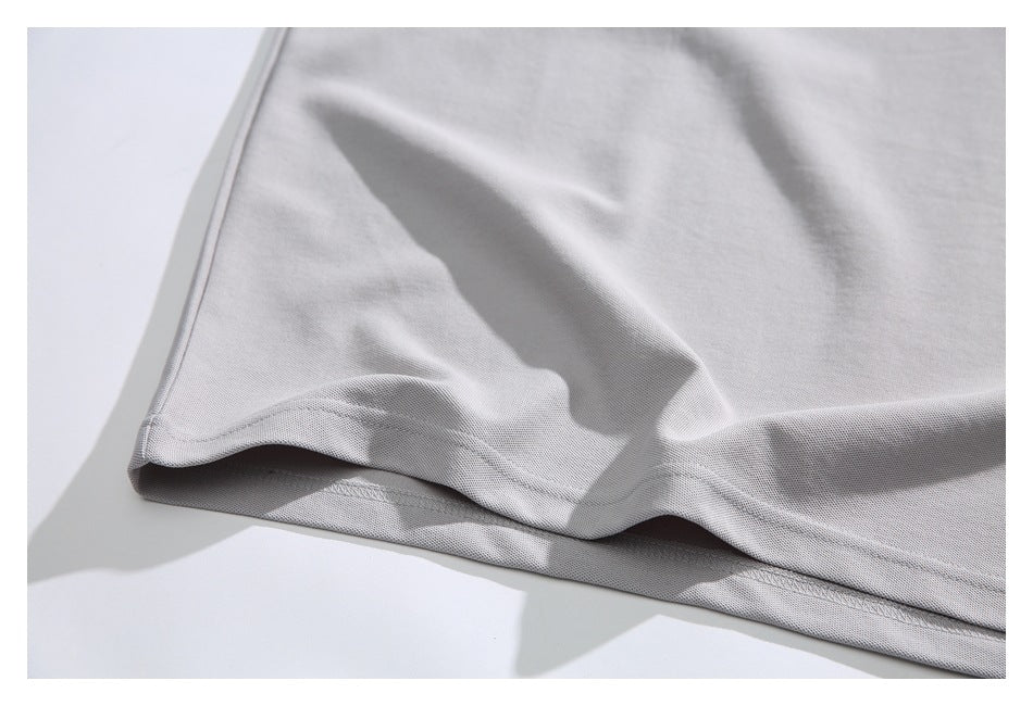 Close-up of the stitched hem on a light gray shirt.