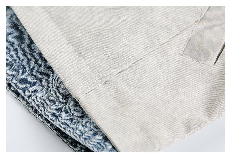 Close-up of a light gray jacket panel and welt pocket beside blue denim fabric.