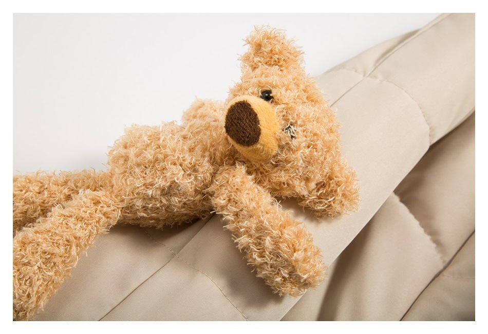 A plush teddy bear rests on the beige quilted jacket.