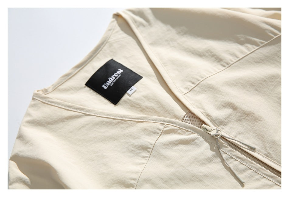 Close-up of the ivory jacket's V-neck, inner label, panel seams, and front zipper.
