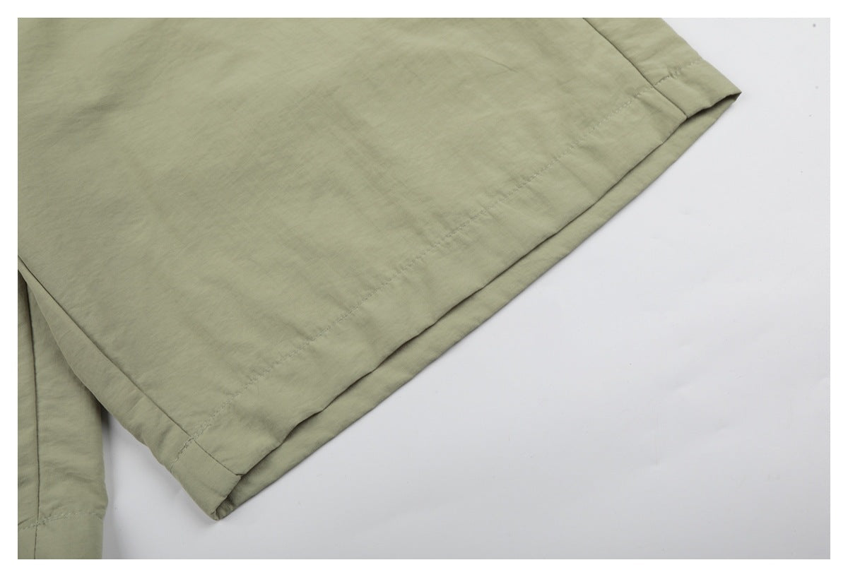 Close-up of a sage-green shorts leg with a stitched hem and folded edge.