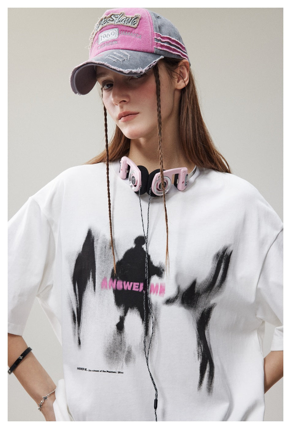Close-up of a model wearing a white T-shirt with black brush-style graphics and pink lettering across the chest.