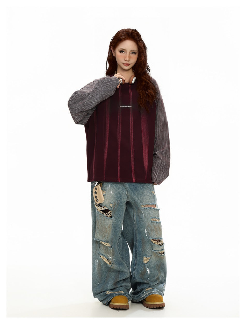 Model wearing a purple oversized raglan sweatshirt with striped sleeves and distressed light-wash jeans, full body