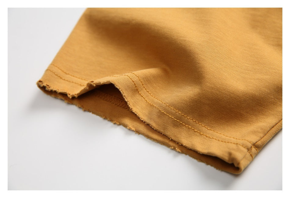 Close-up of the ochre T-shirt's double-stitched sleeve hem and fabric edge.