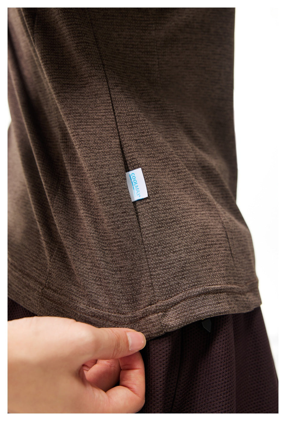 Close-up of the brown top’s textured fabric, hem stitching and small COOLMAX side tag.