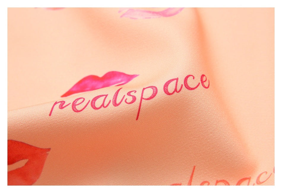 Close-up of peach-colored fabric printed with pink lettering and lip motifs.