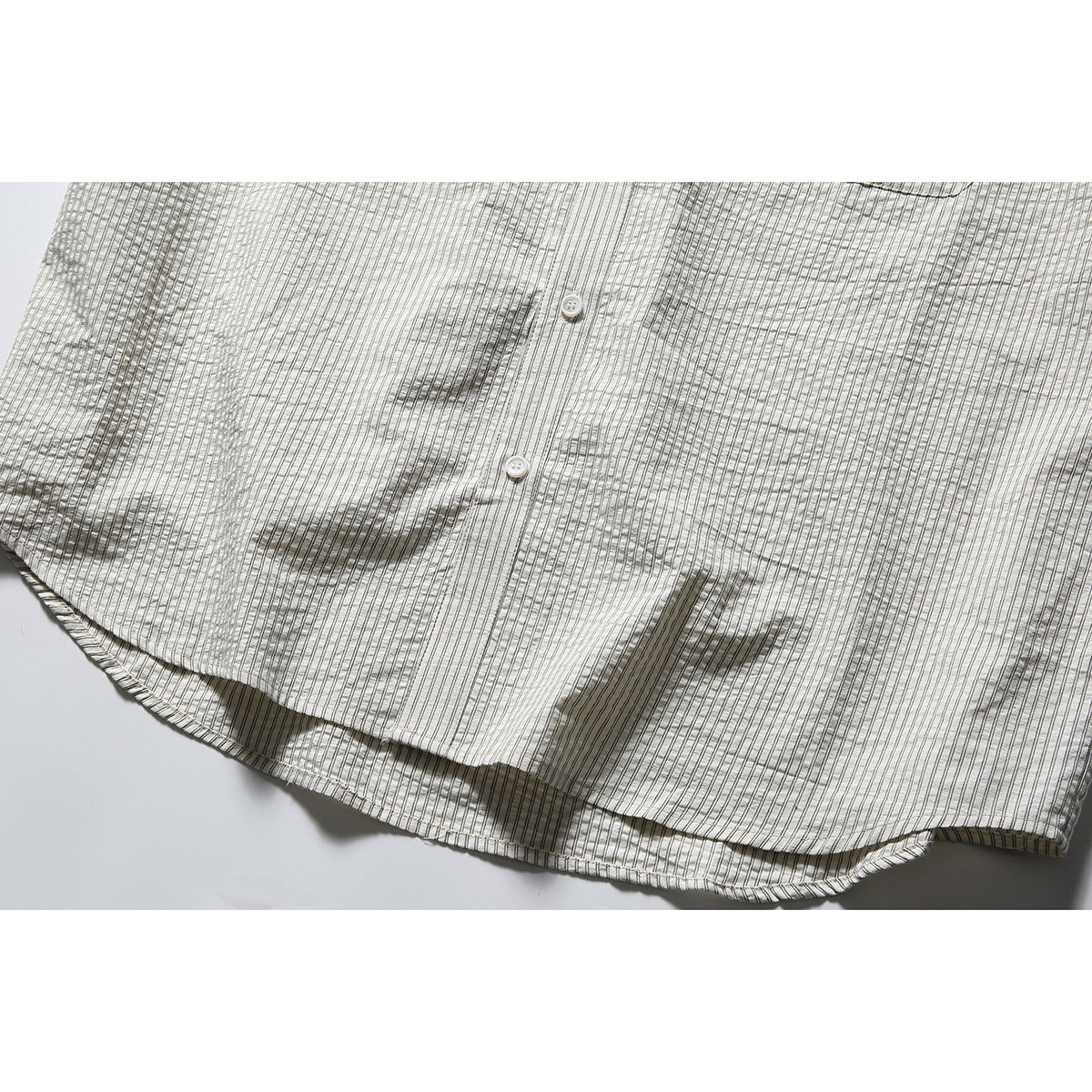 Close-up of the striped shirt's button placket and curved hem.