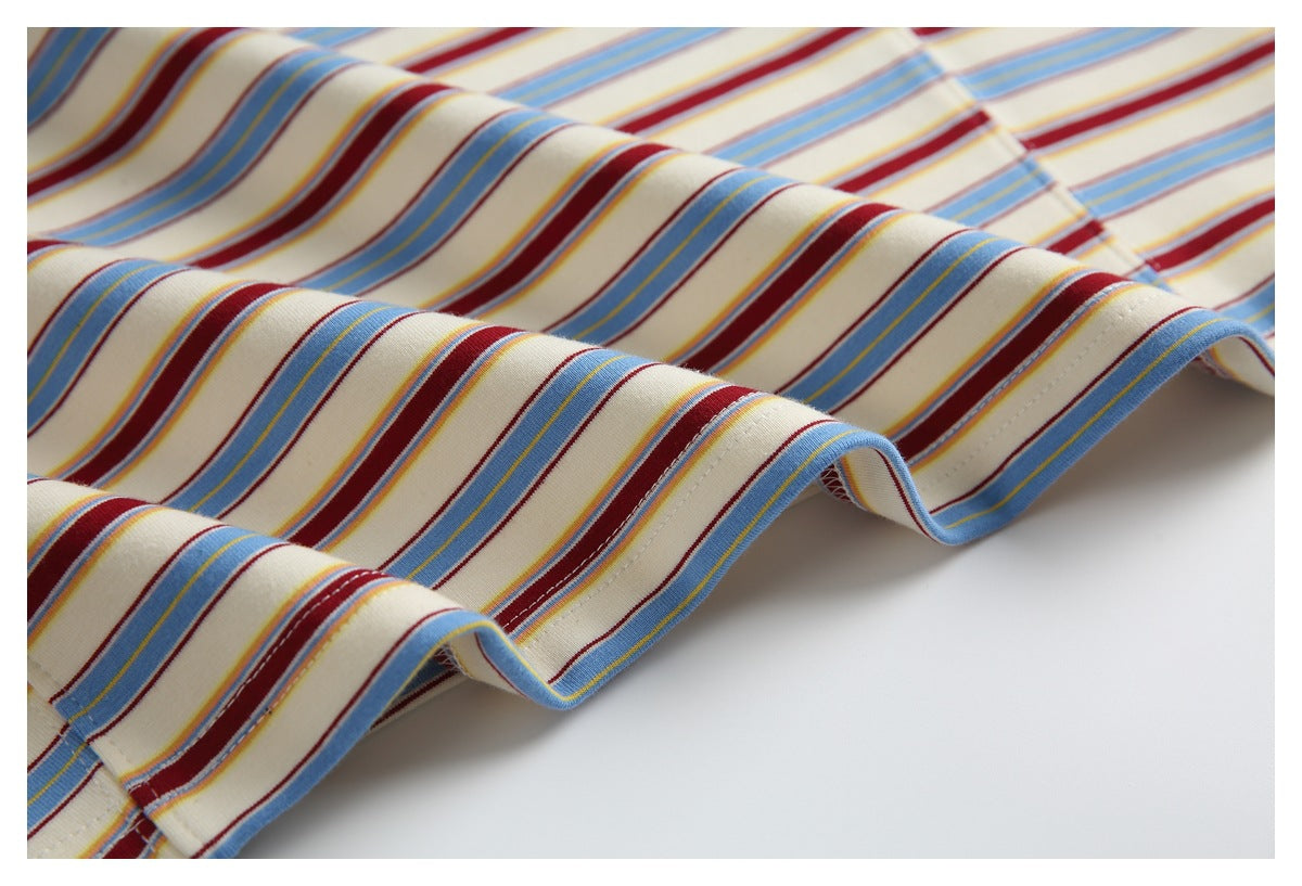 Close-up of the cream T-shirt fabric draped to show its blue, burgundy and yellow stripe pattern.