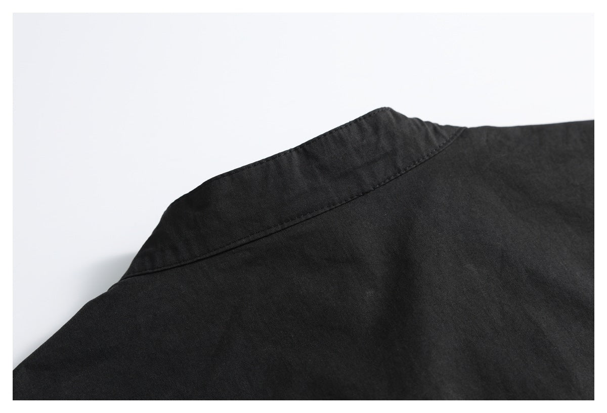 Close-up of a black garment's collar and shoulder seam against a white background.