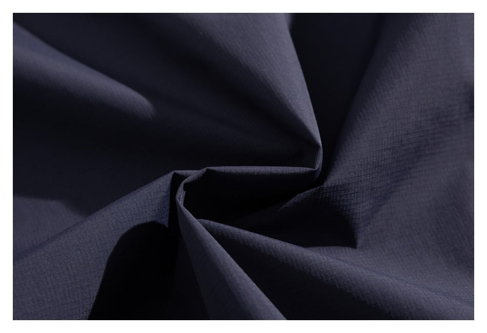Close-up of dark navy jacket fabric gathered into folds, showing its subtle grid texture.