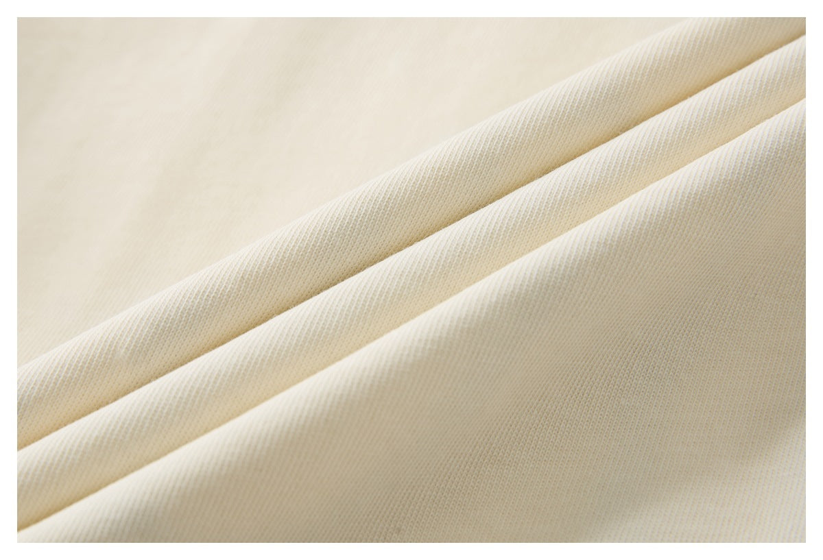 Macro view of cream fabric folded into soft diagonal ridges, showing its surface texture.