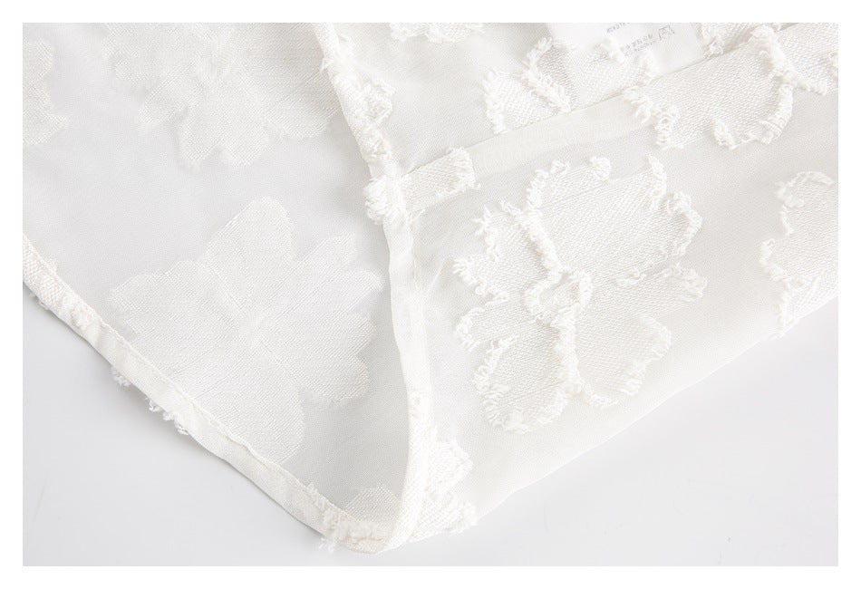 Close-up of ivory floral fabric showing its reverse, finished edges, and a small printed mark.