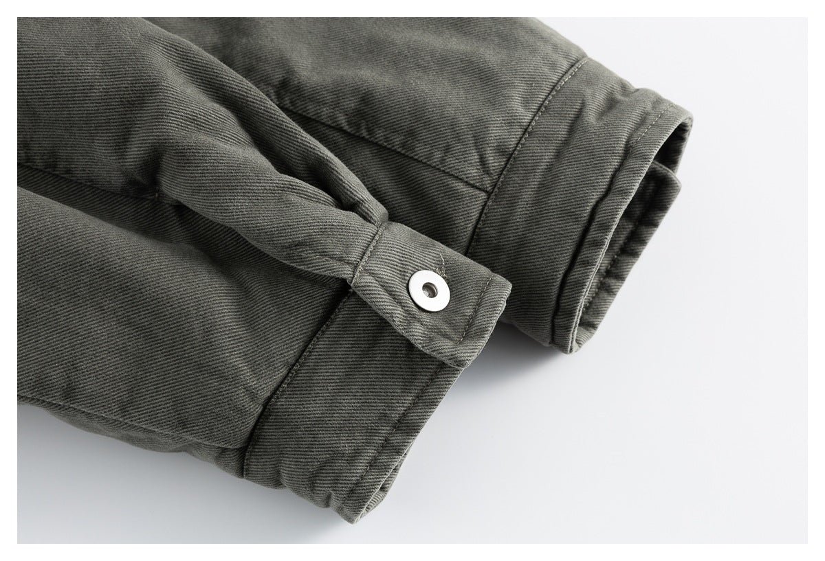 Close-up of an olive-gray jacket sleeve cuff with an adjustable tab and silver snap fastener.