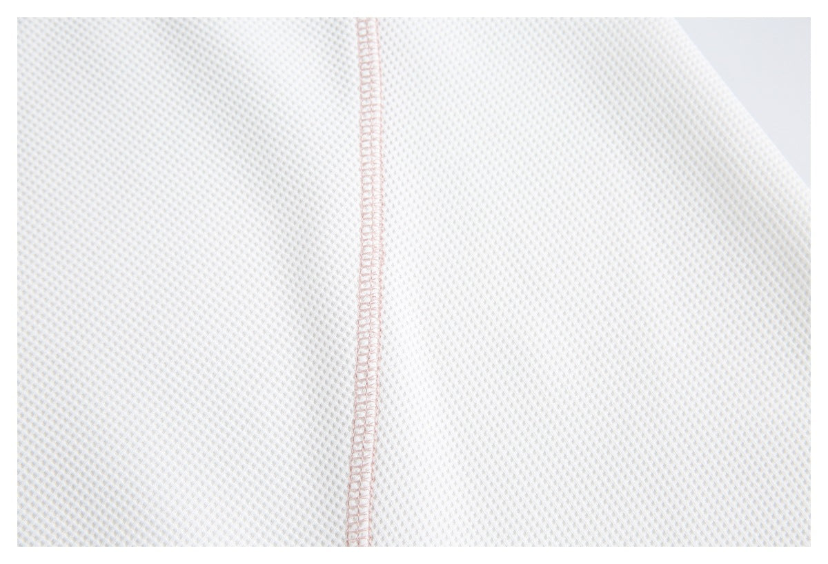 Close-up of white waffle-knit fabric and a vertical pale pink overlocked seam.