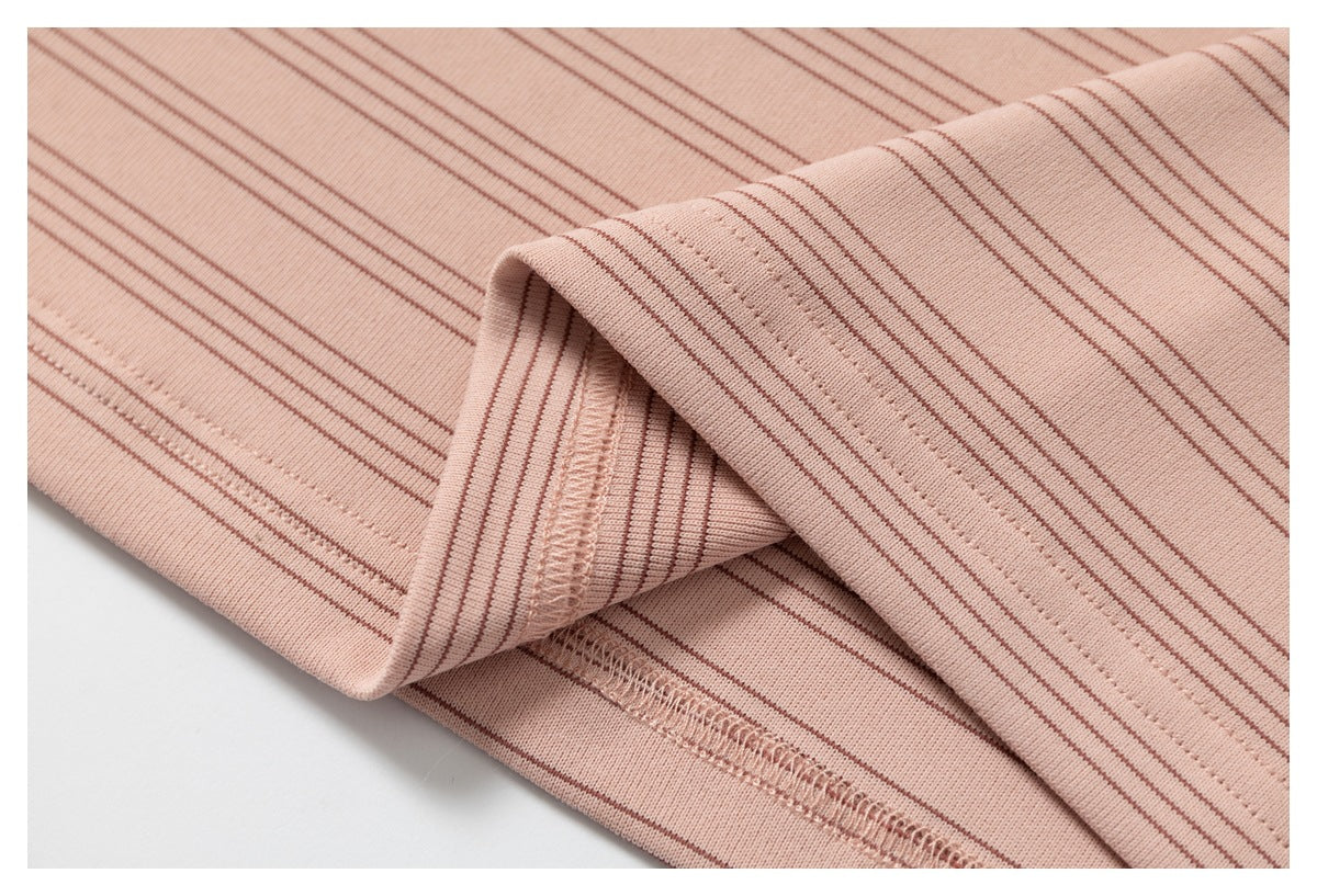 Close-up of a folded edge and overlocked seam on pink fabric with thin brown stripes.