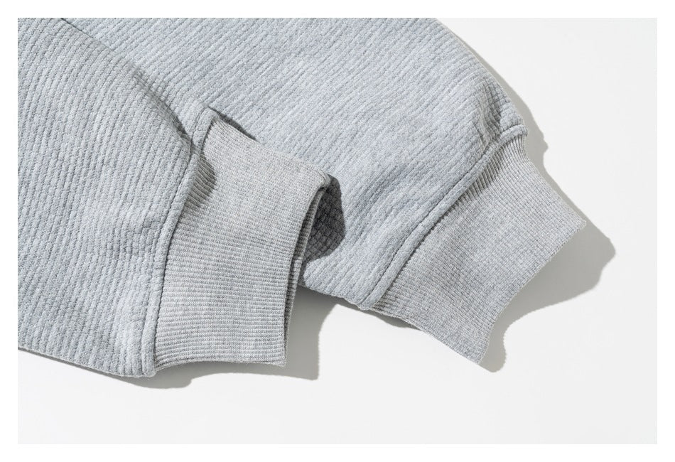 Close-up of a light gray textured sleeve and wide ribbed cuff.