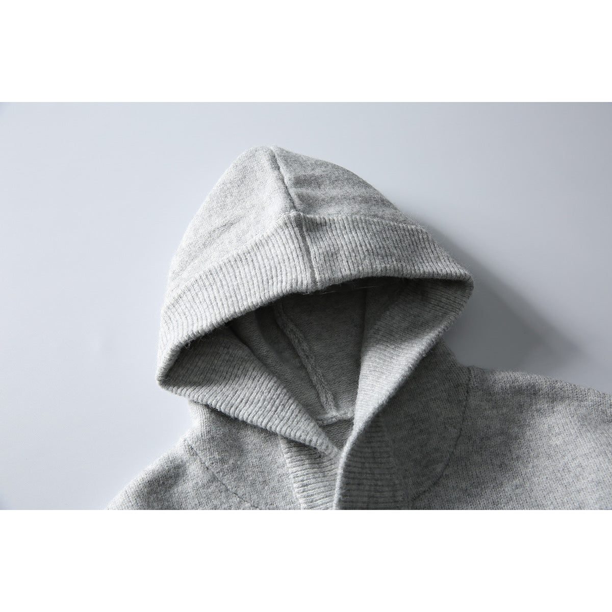 Close-up of a light gray hood and neckline on a knit pullover, with a wide ribbed hood edge.