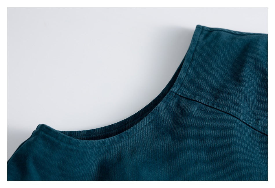 Close-up of a teal garment's curved neckline and shoulder seam.
