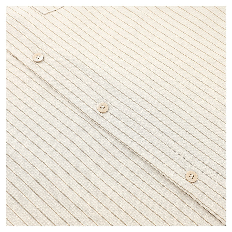 Close-up of the cream shirt's tan-striped button placket.