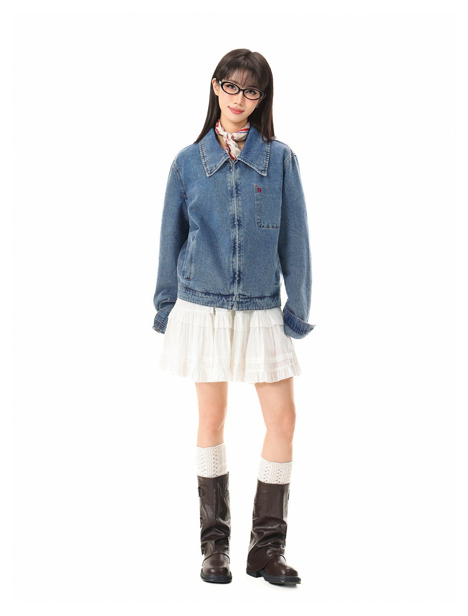 Full-length model wearing a blue denim jacket over a short white ruffled dress, with knit socks and dark boots.