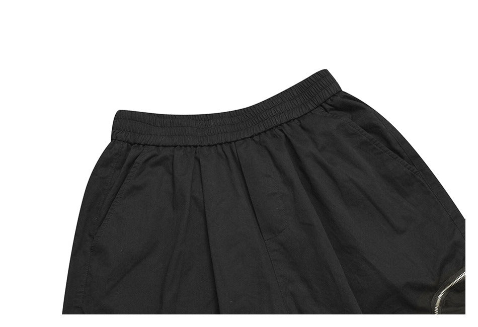 Close-up of black bottoms with an elastic waistband, angled front pockets, and a partial side zipper.
