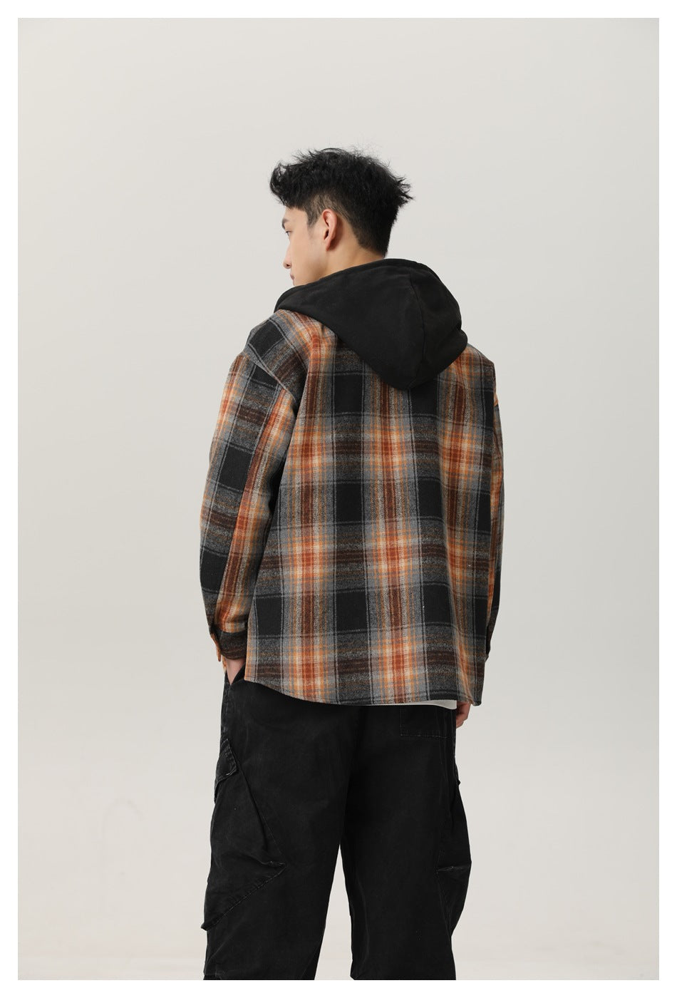 Back view of a man wearing the plaid hooded jacket with black hood and black cargo pants