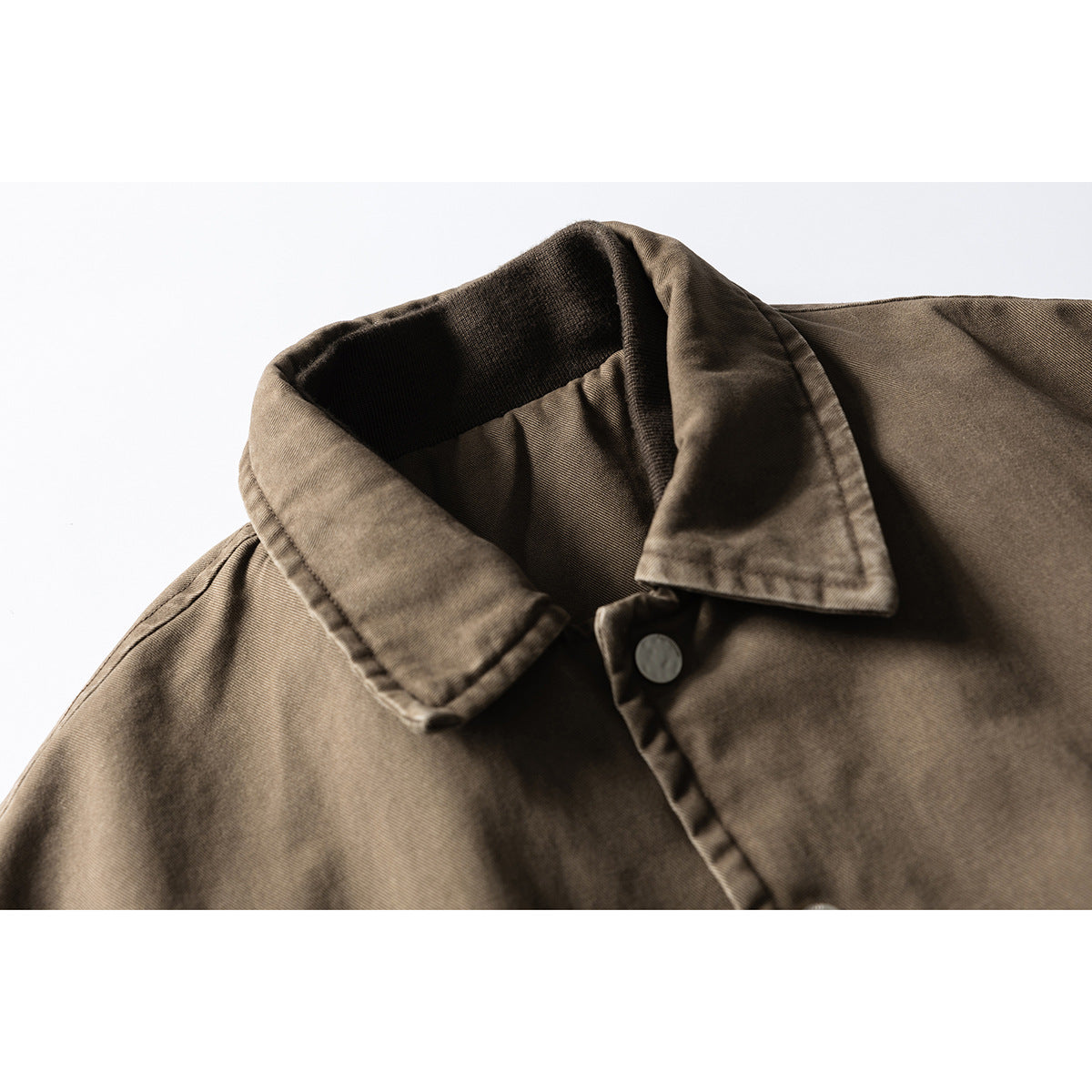 Close-up of the brown jacket's pointed collar, dark ribbed inner neckline, and front button.