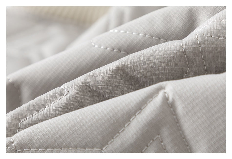Close-up of pale gray fabric with a fine woven texture and visible stitched seams.