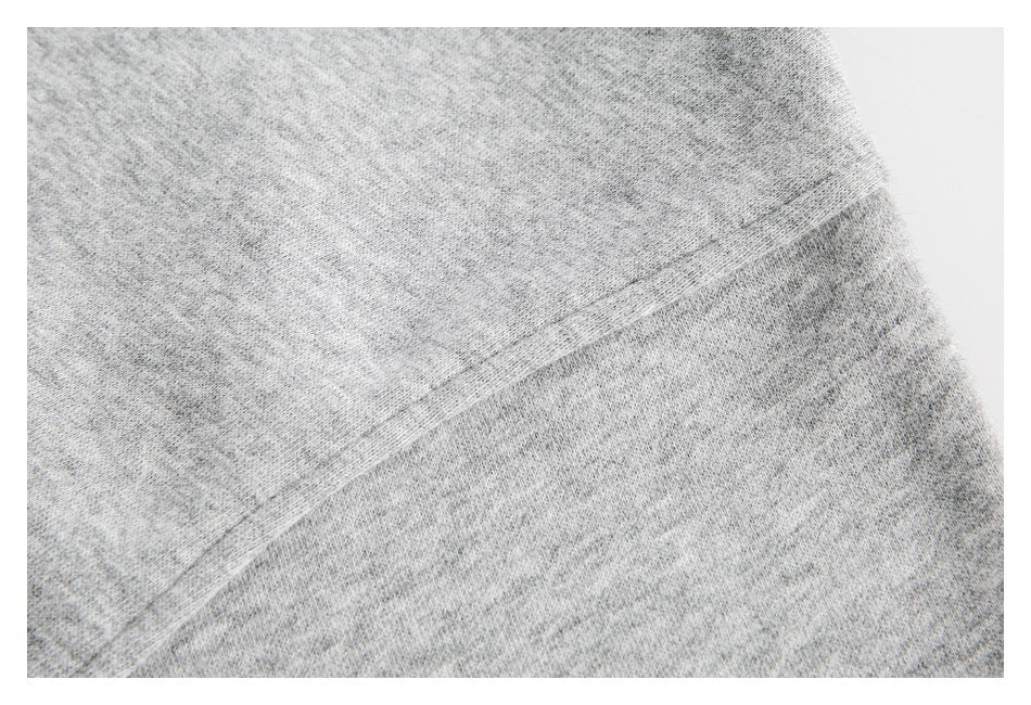 Close-up of a stitched seam across light gray heathered fabric.