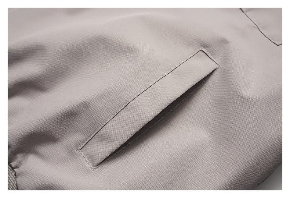 Close-up of a light taupe jacket's narrow welt pocket and stitching.