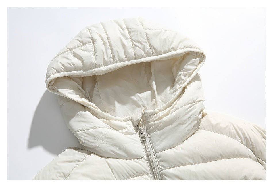 Close-up of an ivory padded jacket's quilted hood and front zipper on a white background.