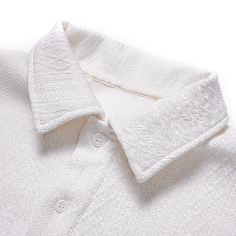 Close-up of a white polo shirt collar, placket, buttons, and raised geometric fabric pattern.