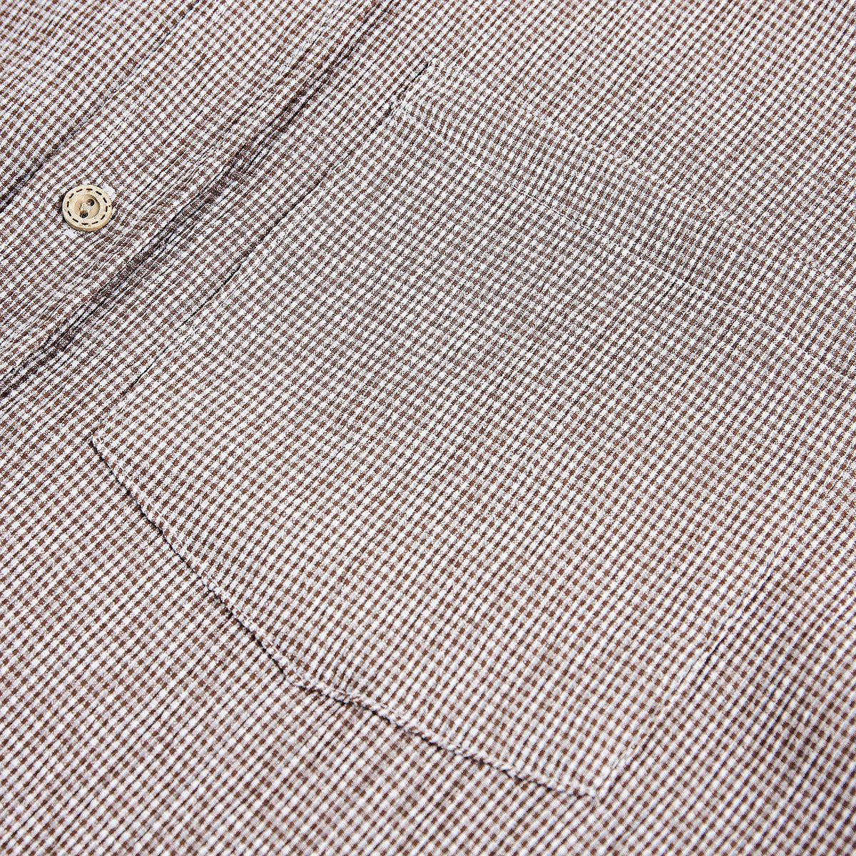 Close-up of brown-and-white check fabric with a tan button and a curved stitched seam.