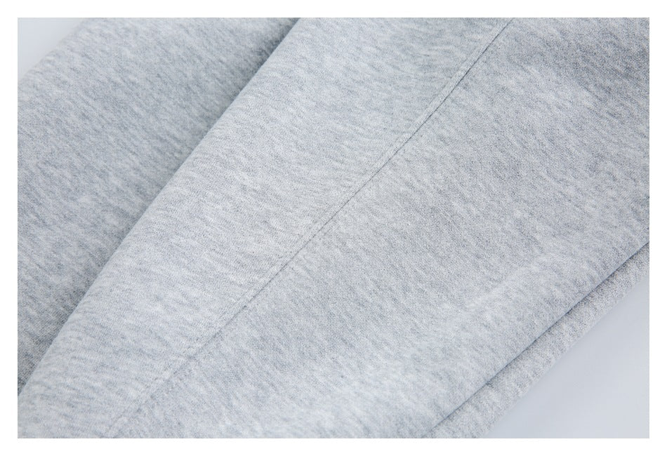 Close-up of a diagonal stitched seam on light gray heathered fabric.