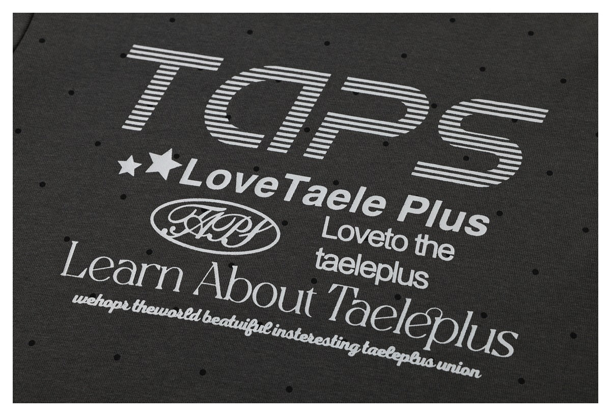 Close-up of a charcoal T-shirt with black dots and a large white graphic featuring English lettering and stars.