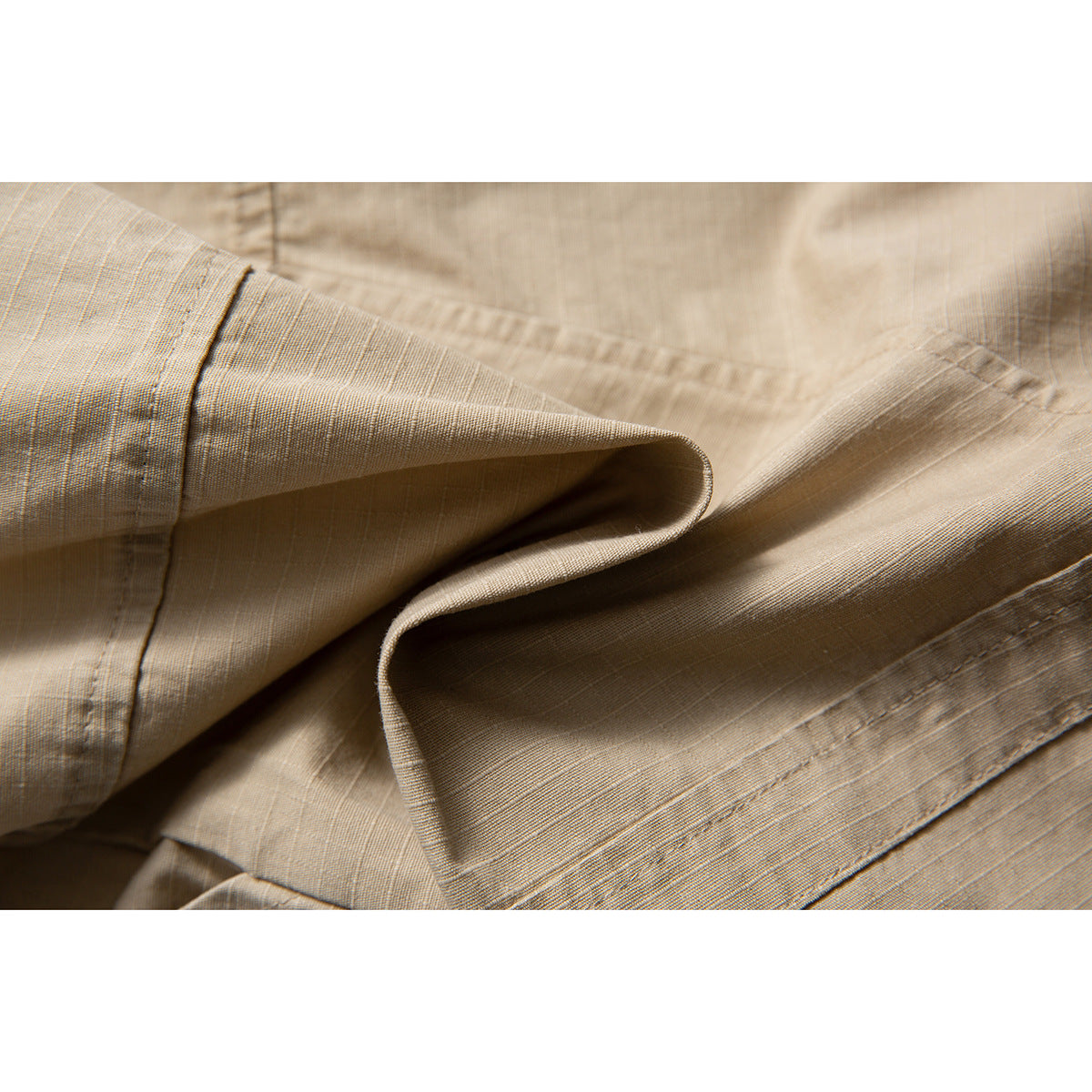 Close-up of folded tan shorts showing the fabric texture, edge stitching, and hem.