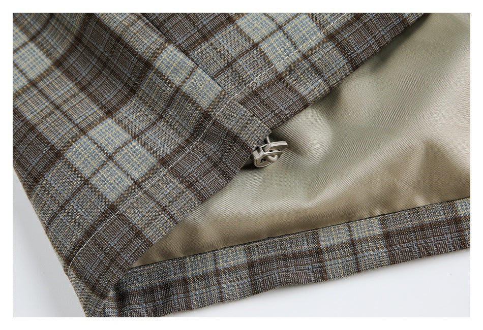 Close-up of a zipper opening at the hem of a brown plaid jacket, showing a khaki inner panel.