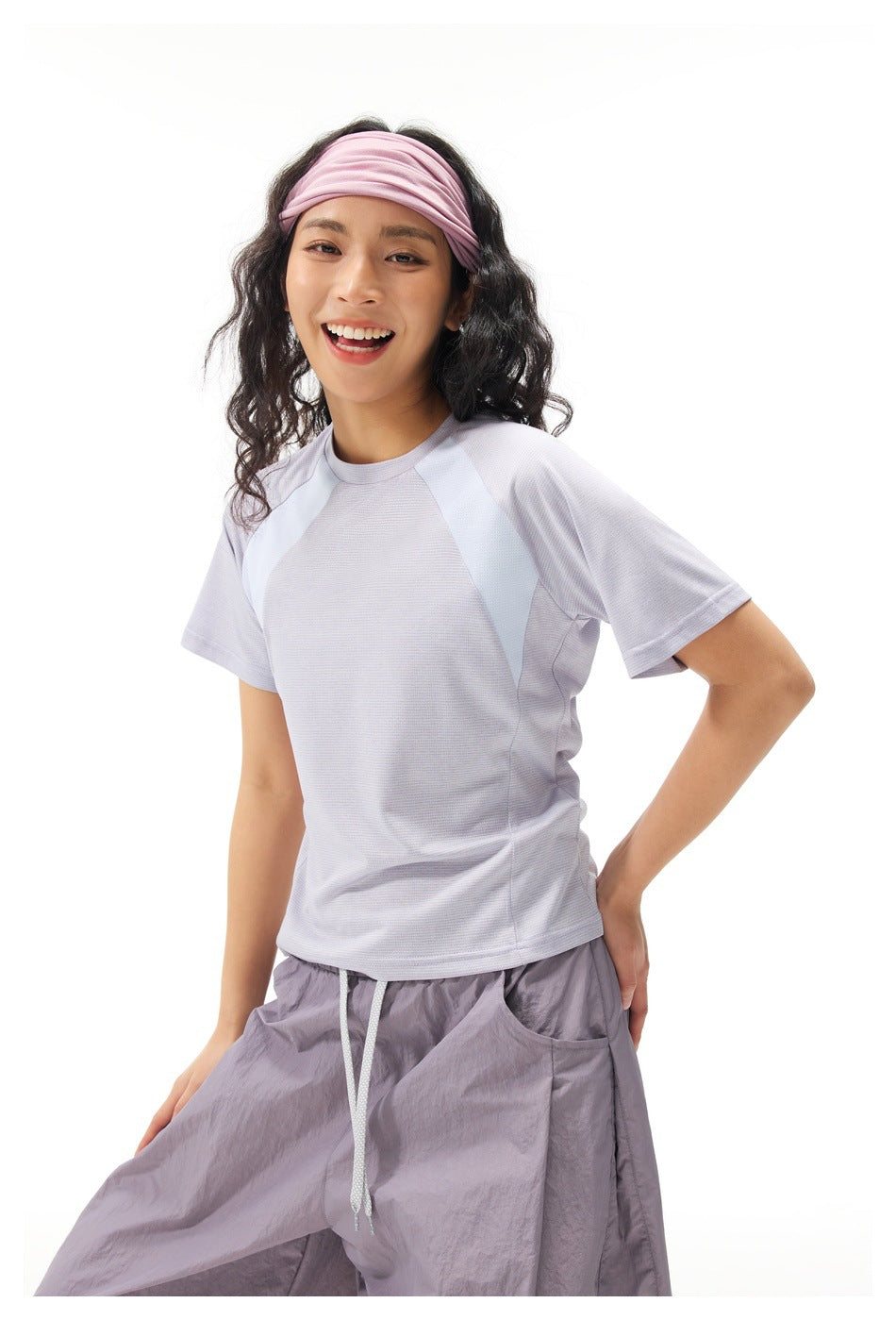 Closer view of the pale lavender T-shirt with light blue shoulder panels, worn with loose lavender-gray pants.