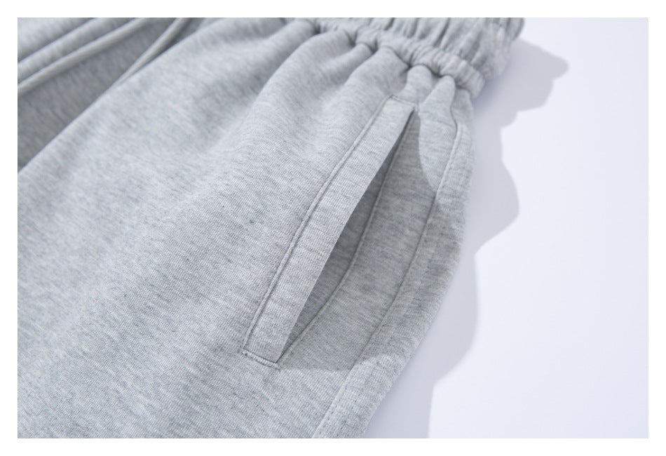 Close-up of light gray sweatpants showing an elastic waistband and slanted side pocket.