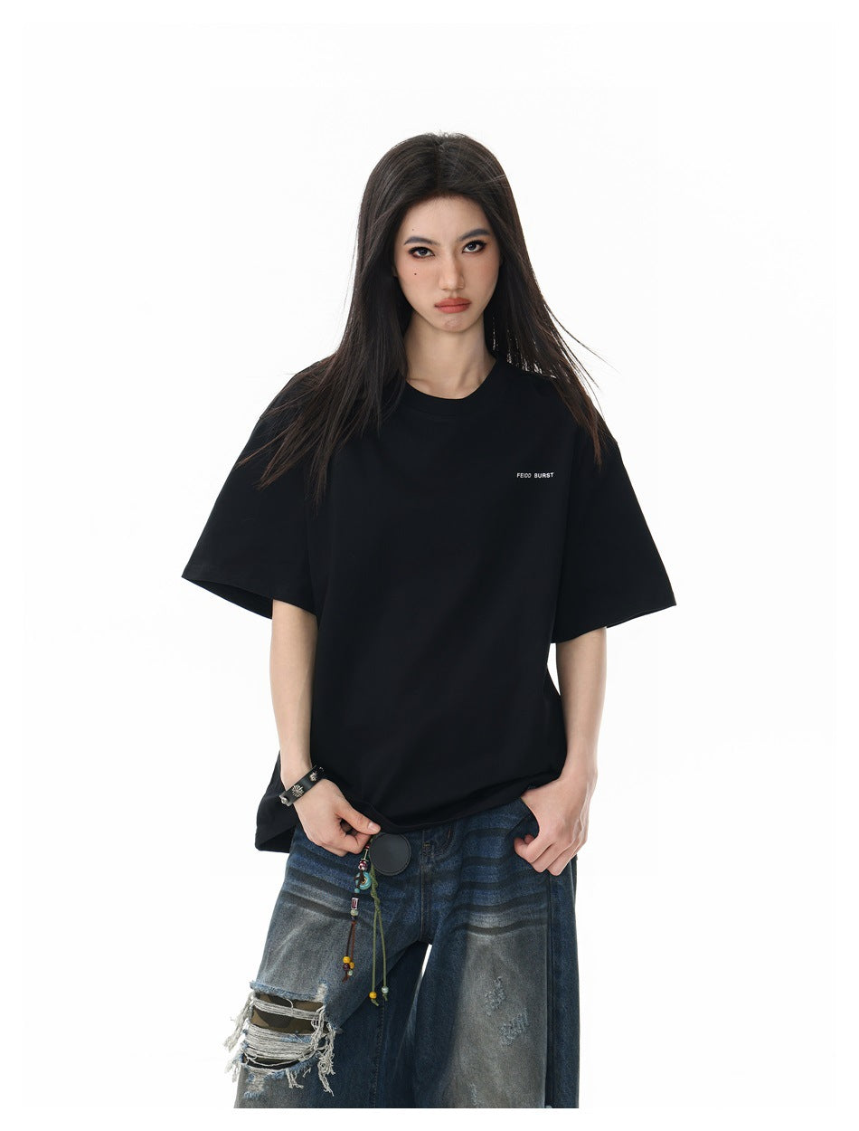 Front view of a model wearing an oversized black T-shirt with small white chest text and distressed blue jeans.