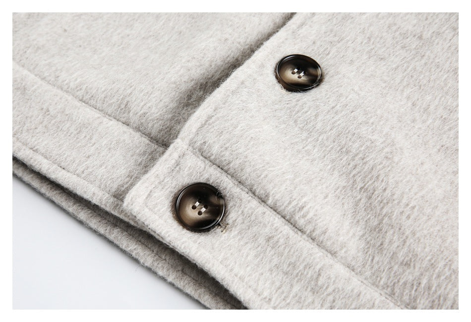 Close-up of two dark buttons and a stitched edge on a cream coat.