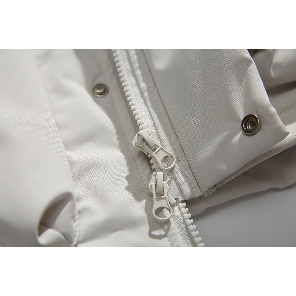 Close-up of the ivory vest’s chunky front zipper, dual pulls and metal snaps.